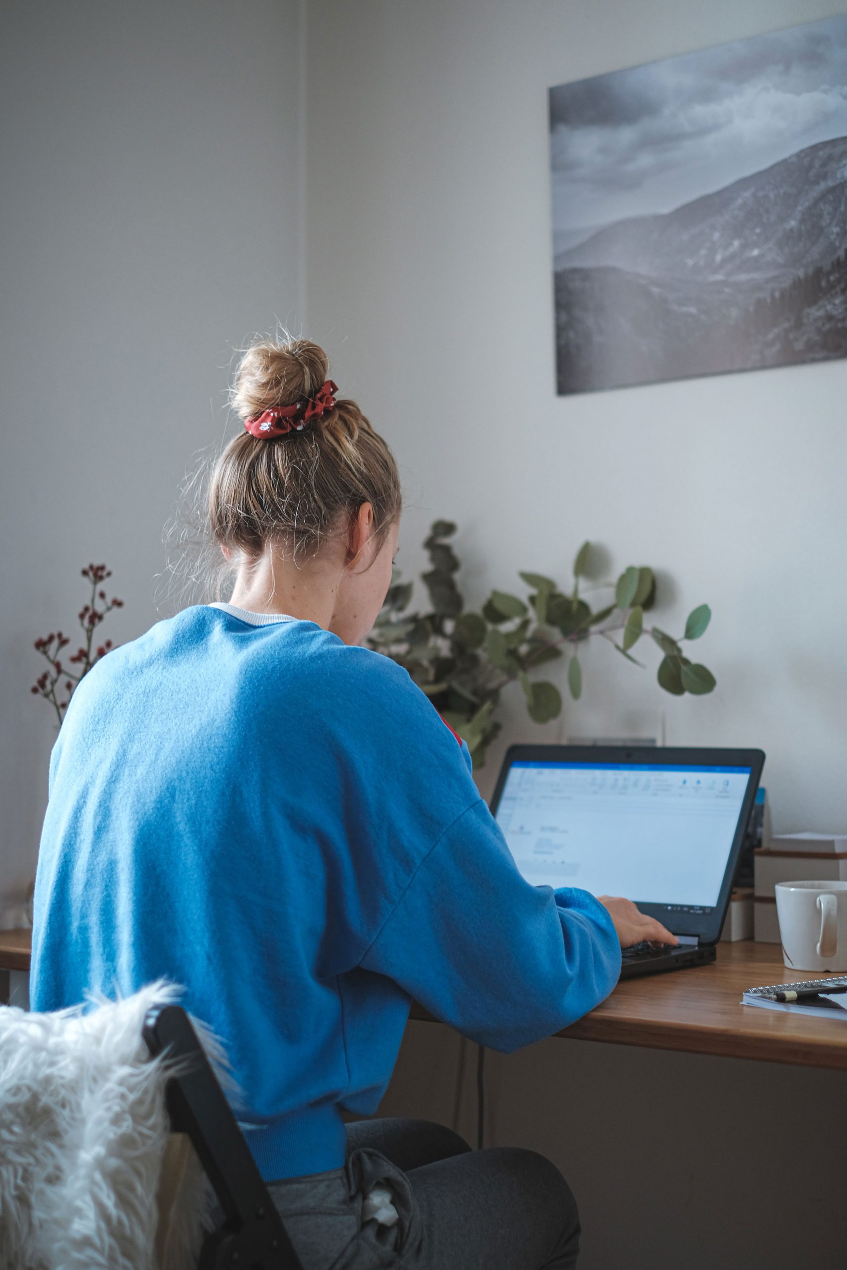 Woman using modern workplace solutions to work remotely at desk with her laptop.