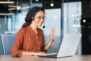 Customer service woman agent smiling and waving at laptop.