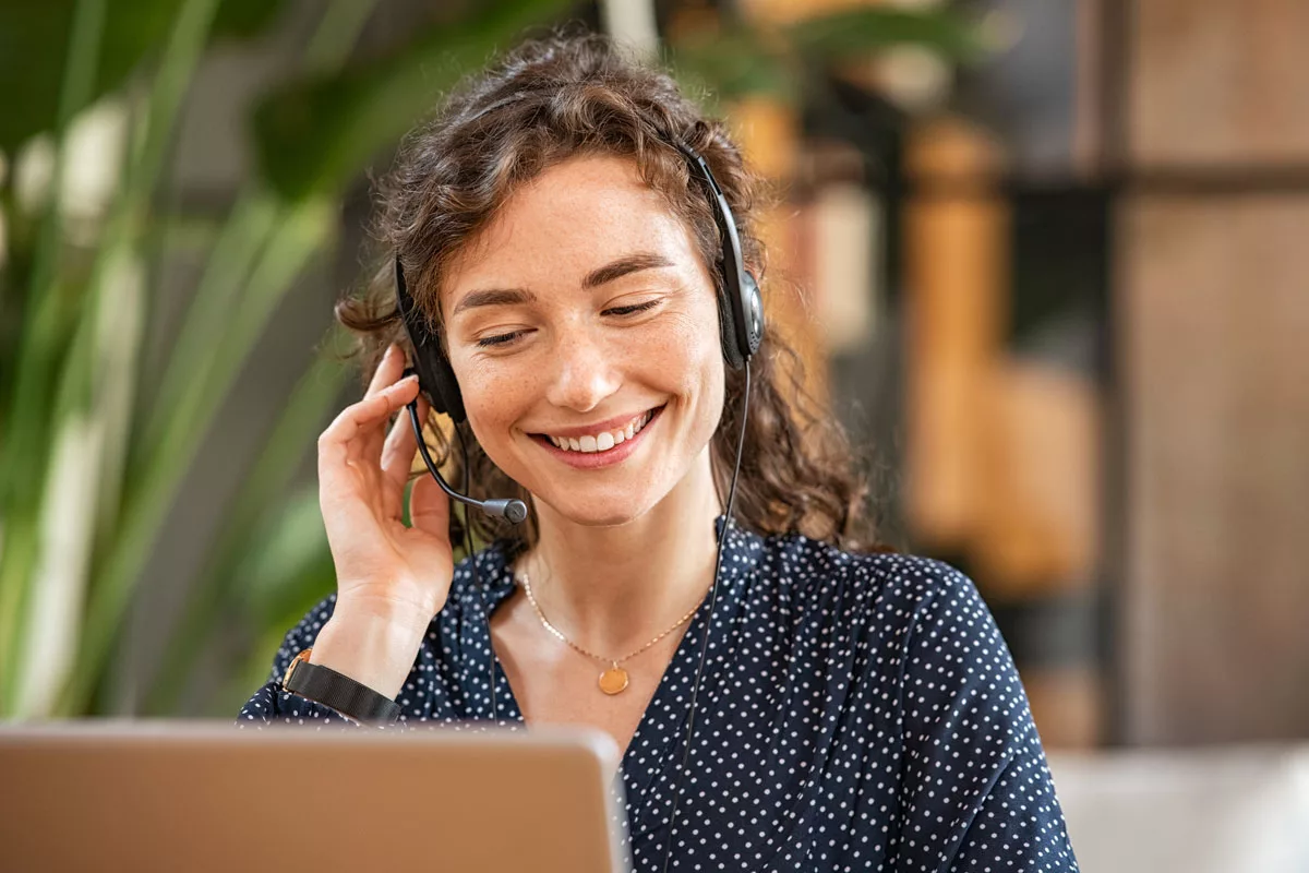 A woman smiling while providing customer support over the computer.